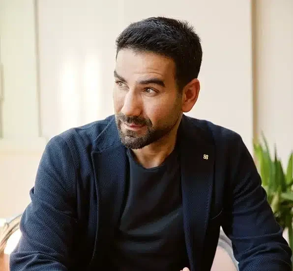 Op. Dr. Süleyman Özer Kimdir? | Estetik Cerrahi Uzmanı Biyografisi Dr. Süleyman Özer beyaz önlük ve gülümseyen yüz ifadesiyle klinikte